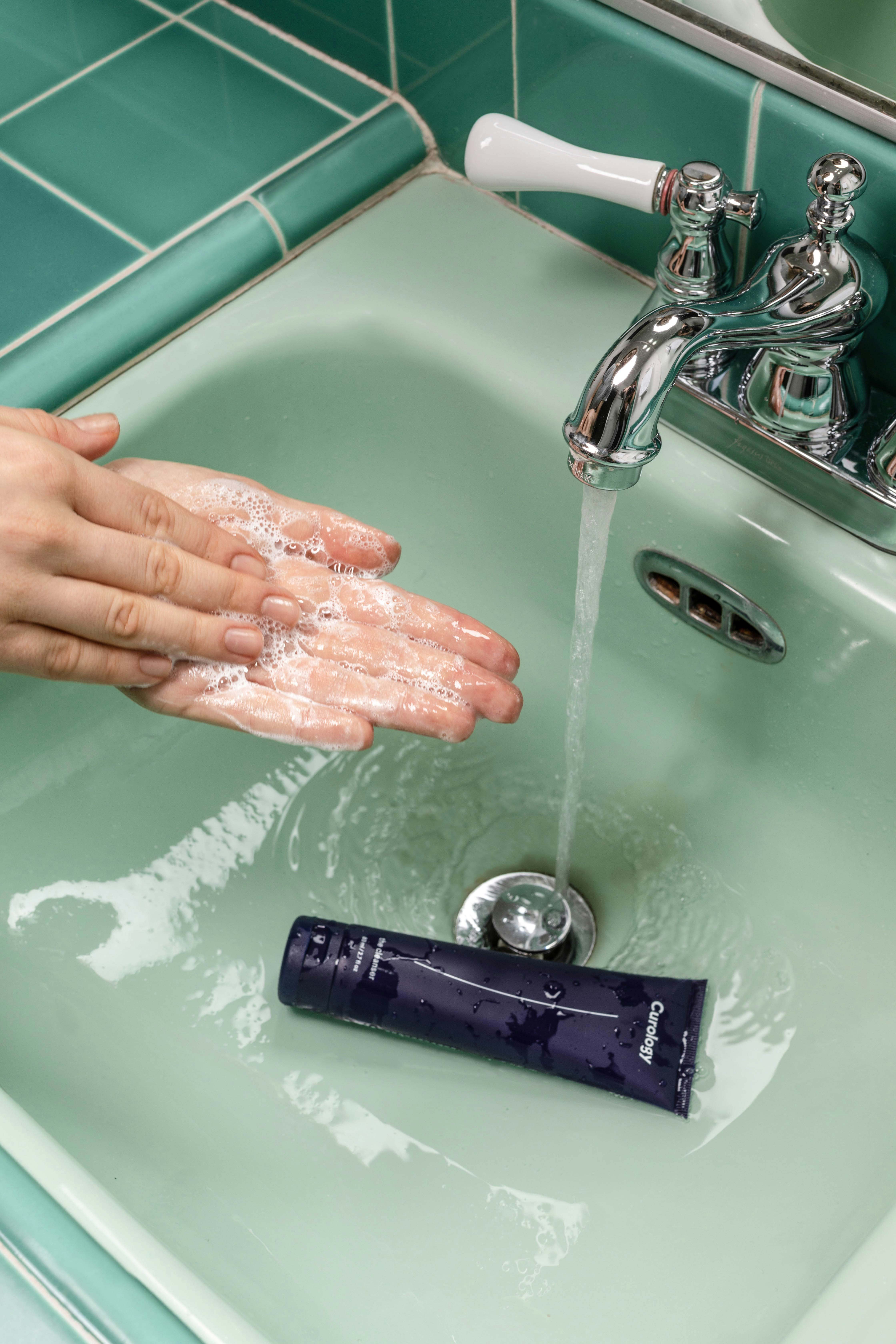 A person washing their hands under a faucet